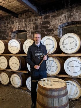 Drew Hannush holding a whiskey thief in Bushmills warehouse